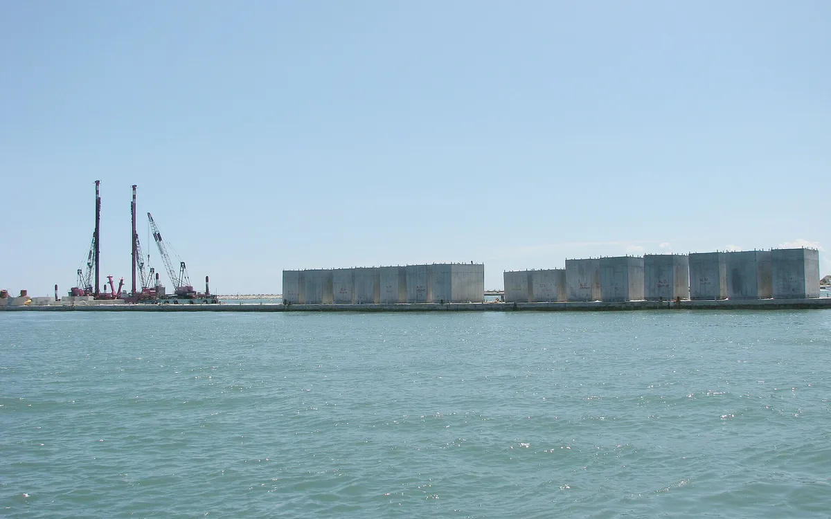 Caissons for the MOSE flood barrier under construction in the Venice lagoon, with floating cranes alongside